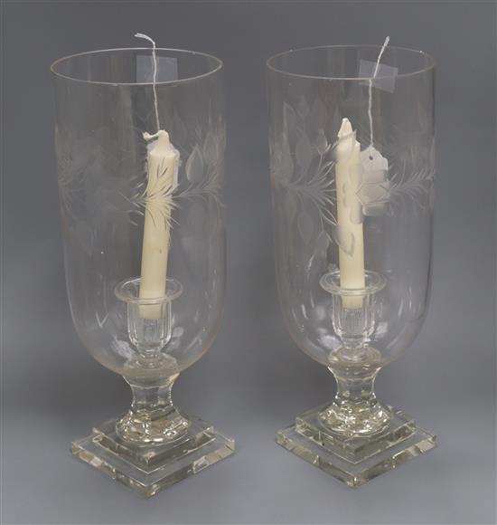 A pair of glass storm candle holders, each engraved with foliate band H 38cm